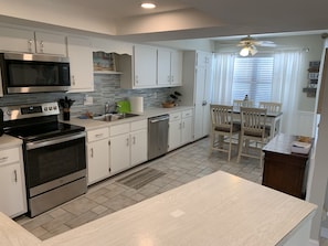 A modern kitchen with stainless steel appliances, white cabinetry, and a dining area with wooden chairs. - The Perfect Relaxing Retreat, close to beach,  parks, and bike/walking (Cape Coral)