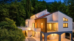Ein modernes, zweistöckiges Haus mit Balkon, Swimmingpool und einem gepflegten Garten.