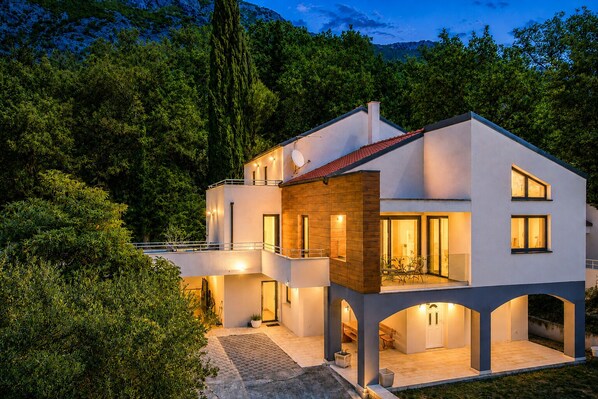 Ein modernes, zweistöckiges Haus mit Balkon, Swimmingpool und einem gepflegten Garten.