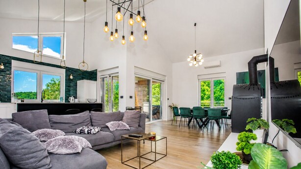 Ein modernes Wohnzimmer mit Sofa, Couchtisch und Essbereich mit Stühlen.