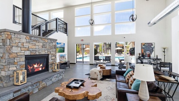 Un vestíbulo amplio con chimenea de piedra, una escalera y vistas a la piscina.