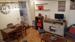 Ett kompakt bostadsutrymme med en matplats, ett litet kök och en sittgrupp.