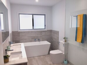 Bañera con ducha, toallas, papel higiénico