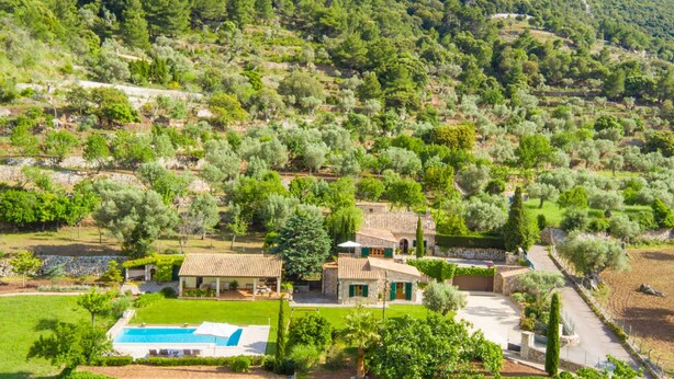 Une villa avec piscine, entourée d’une végétation luxuriante et de champs en terrasses.