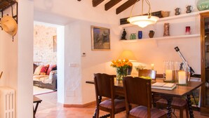 Un coin repas accueillant, avec une table dressée pour deux personnes, entourée de chaises en bois. Un vase rempli de fleurs orange apporte une touche de couleur vive.