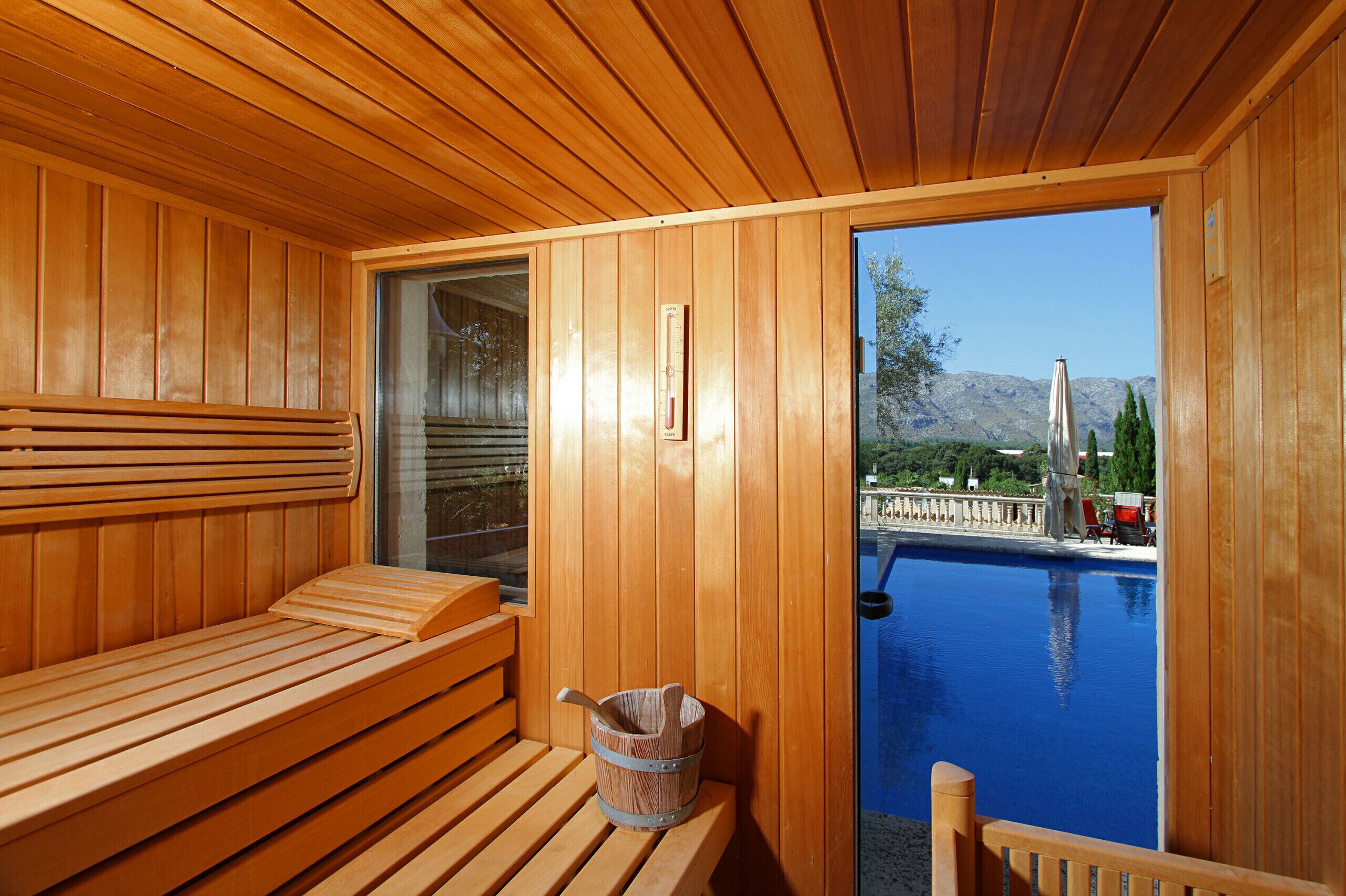 Eine Holzsauna mit Bänken und Blick auf ein Schwimmbad.
