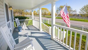 A porch with white railings, a blue vase, and an American flag. - North Cottage at Hobbit Hollow Farm (Skaneateles)