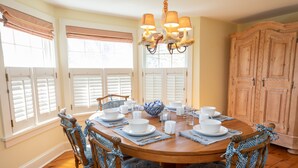 A dining room with a wooden table set for four, surrounded by four chairs with blue patterned cushions. - North Cottage at Hobbit Hollow Farm (Skaneateles)