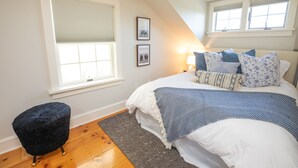 A bedroom with a bed, a small stool, a window, and two framed pictures on the wall. - North Cottage at Hobbit Hollow Farm (Skaneateles)