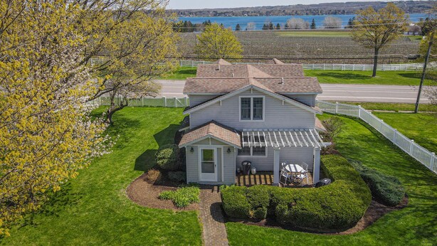 A two-story house with a covered porch and a small garden. - North Cottage at Hobbit Hollow Farm (Skaneateles)