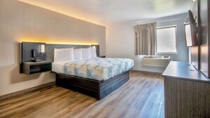 A modern hotel room with a bed, bedside table, and a desk with a chair. - Studio 6 Georgetown, KY – Lexington North (Georgetown)