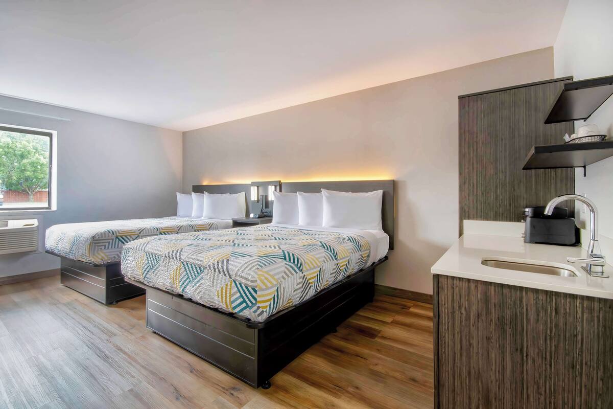 A modern bedroom with two beds, a built-in wardrobe, and a bedside table.