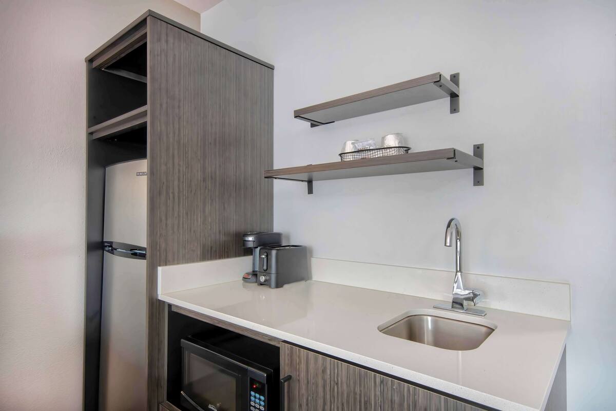 A compact kitchen with a built-in microwave, a coffee maker, and a sink.
