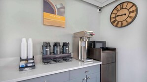 A modern kitchen area with a coffee machine, cups, and a clock on the wall. - Studio 6 Georgetown, KY – Lexington North (Georgetown)