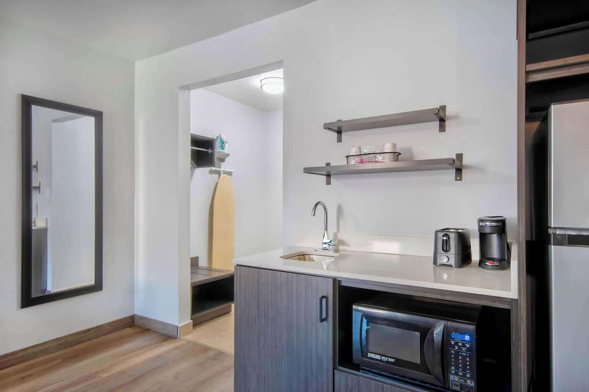 A modern kitchen with a built-in microwave, a sink, and a coffee maker on the countertop.