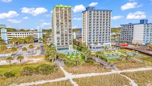 A high-rise hotel with multiple floors, a parking area, and a pool with sun loungers. - Meridian 705 (Myrtle Beach)