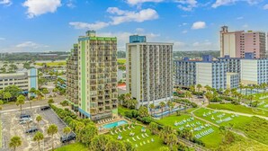 A high-rise hotel with multiple floors, a swimming pool, and a well-maintained garden with sun loungers. - Meridian 705 (Myrtle Beach)