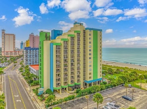 Ein mehrstöckiges Hotel mit Balkonen, einem Parkplatz und Blick aufs Meer.