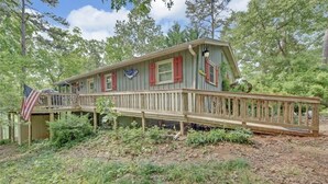 A wooden cabin with a deck, surrounded by trees. - THIRTEEN FEET of water at our dock currently SUPER CUTE On the lake, Deep Water  (Hartwell)