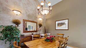 A dining room with a wooden table, chairs, a chandelier, a mirror, and wall-mounted lights. - Free SkyCard Act-Home, Private Hot Tub, Perfect For Large Families-Gold King Cha (Breckenridge)