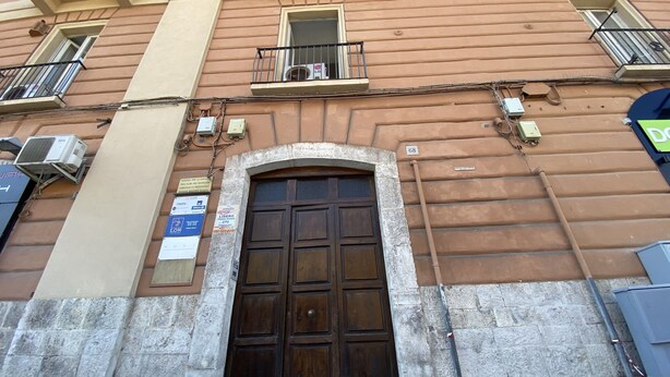 Un edificio con un gran puerta de madera, varios balcones y unidades de aire acondicionado.
