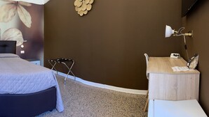 Un dormitorio con cama, tocador, espejo y zona de ducha.