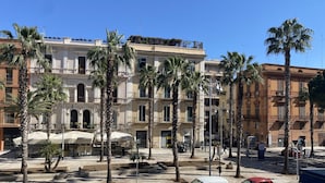 Vista de la calle con coches aparcados, palmeras y edificios con balcones.