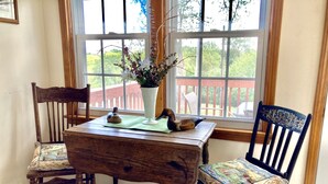 A wooden table with two chairs, a vase with flowers, and a decorative duck.