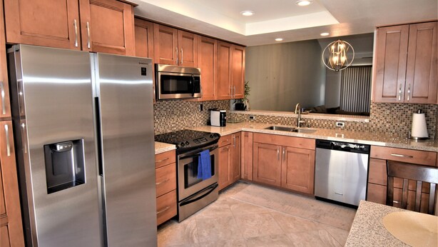 A modern kitchen with stainless steel appliances, wooden cabinets, and a tiled backsplash. - Palm Valley CC Remodeled beauty, 2b 2ba on 6th fairway w/golf cart, club access. (Palm Desert)