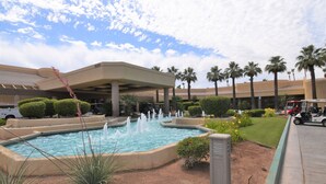 A landscaped pool area with fountains, palm trees, and a building with a curved roof. - Palm Valley CC Remodeled beauty, 2b 2ba on 6th fairway w/golf cart, club access. (Palm Desert)