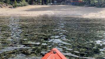 Un kayak sur une étendue d’eau claire, avec une zone boisée en arrière-plan.