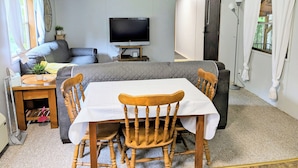 A cozy living room with a TV, sofa, and dining area with chairs. - Backroad Pines Hideaway
Your ATV & Waterfall Adventure Basecamp! (Dunbar)