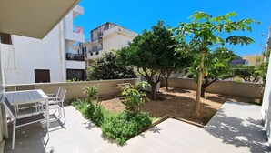 A patio area with a table and chairs, surrounded by greenery and a tree. - Deluxe house, 5 min. walk from Old Town, Acropolis and city centre. Free Wi-Fi. (Ρόδος)