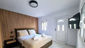 A modern bedroom with a wooden accent wall, a bed with white linens, a nightstand, and a door with a mirror. - Deluxe house, 5 min. walk from Old Town, Acropolis and city centre. Free Wi-Fi. (Ρόδος)