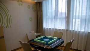 Ein Hotelzimmer mit einem für vier Personen gedeckten Esstisch, einem kleinen Beistelltisch und einem großen Fenster mit durchscheinenden Vorhängen.