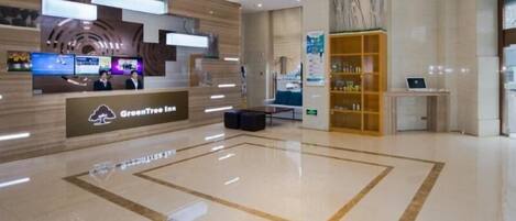 Un vestíbulo de hotel con una recepción, una zona de estar y una exhibición de servicios.