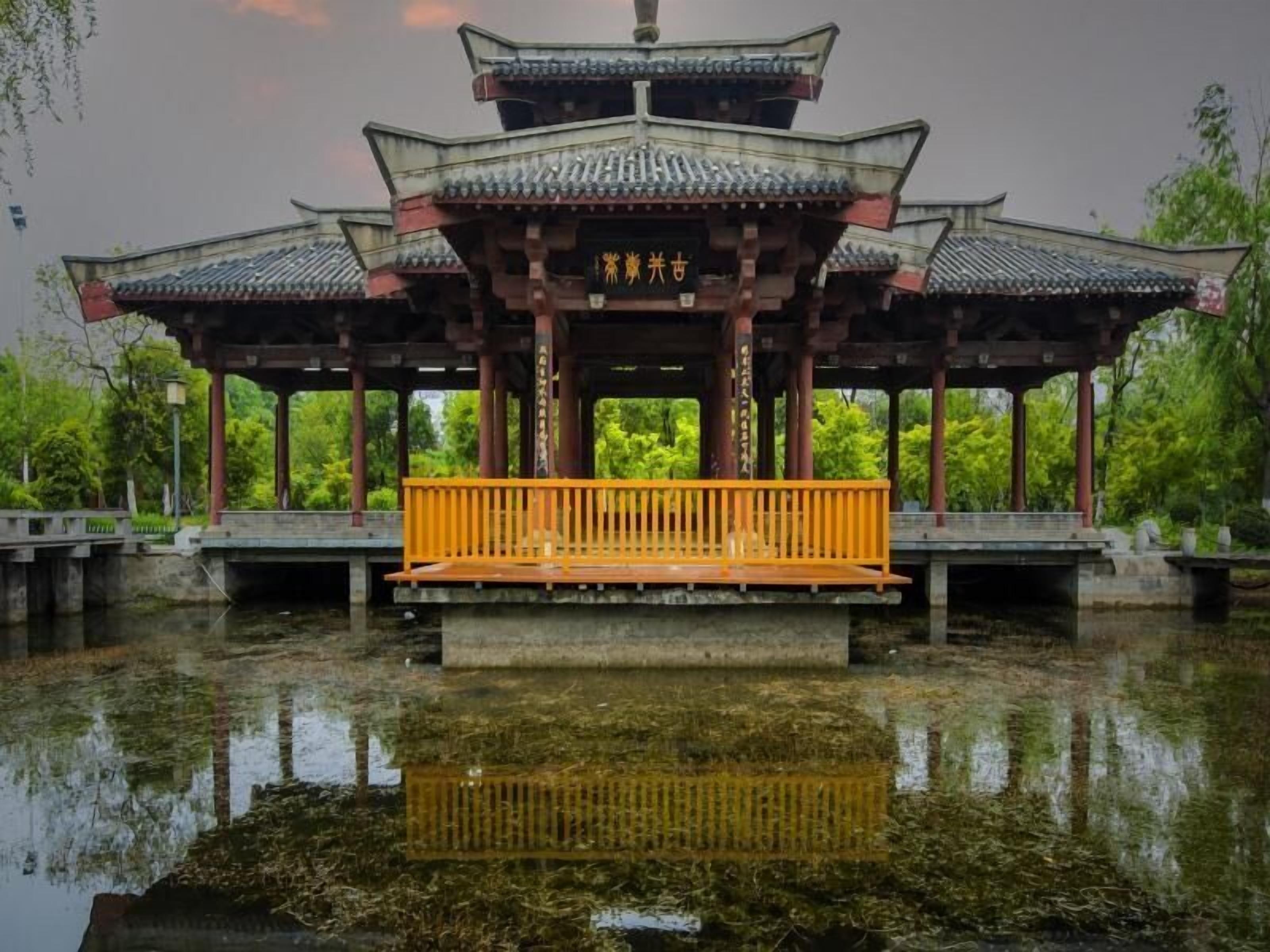 A traditional pavilion with a central open space and a bench.