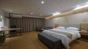 Ein modernes Hotelzimmer mit einem großen Bett, einem Schreibtisch, einem Sessel und einem kleinen Tisch.