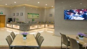 Eine Hotelhalle mit Empfangsschalter, Sitzgelegenheiten und einem Fernseher, der eine Szene zeigt.