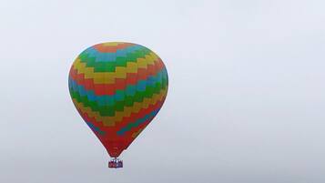 A hot air balloon with a colorful pattern, flying over a green landscape.