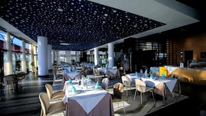 En rummelig restaurant med dækkede borde, et loft med stjernemønster og store vinduer der lukker naturligt lys ind.
