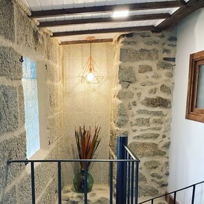A stone interior with a hanging light fixture, a window, and a railing.