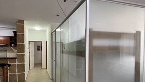 A hallway with a kitchen area on the left, featuring a tiled floor and a wooden chair.