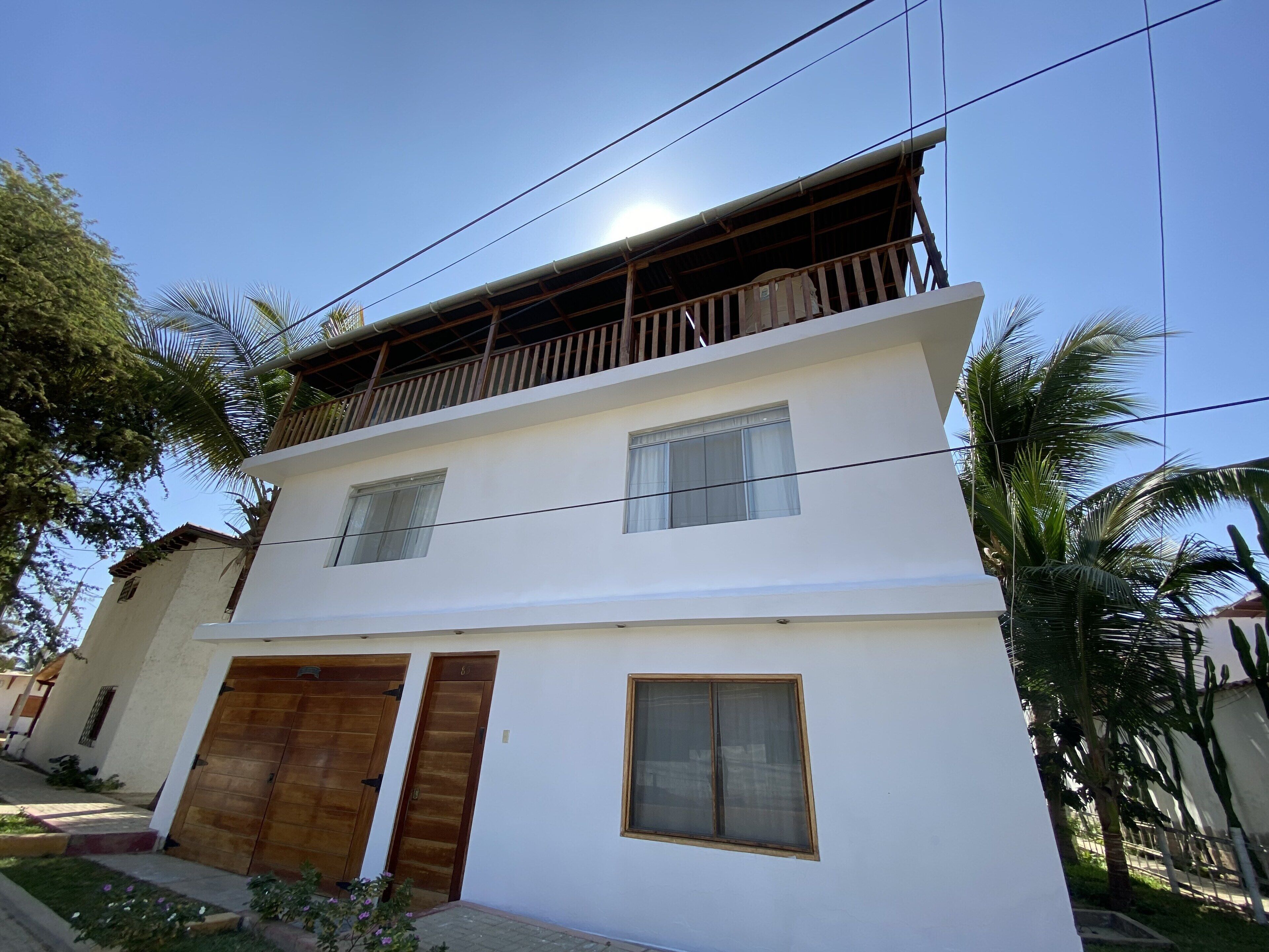 A two-story building with a balcony on the upper floor, a wooden door on the ground floor, and a small window.