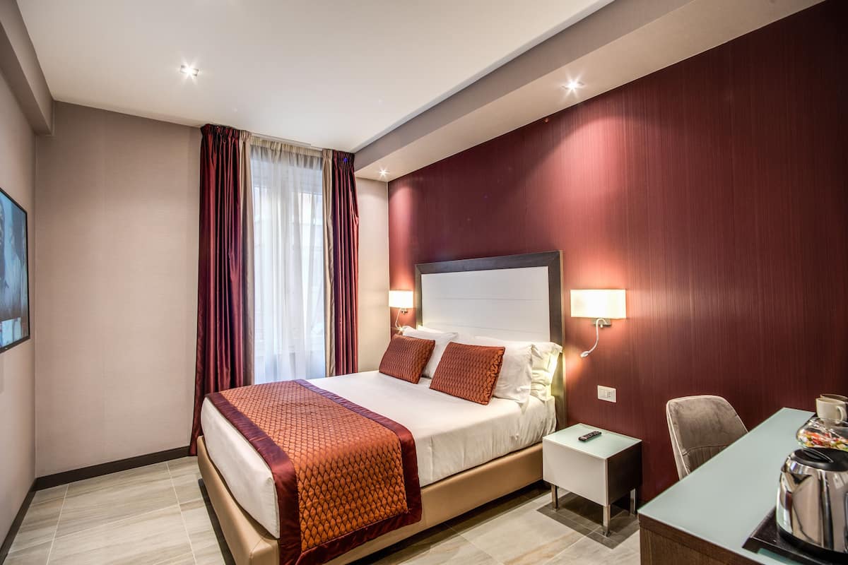 A hotel room with a large bed, bedside tables, a desk, and a chair.