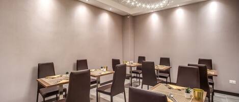A conference room with a modern design, featuring a central table surrounded by chairs, a decorative ceiling light, and a neutral color scheme.