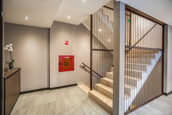 Un interior moderno con una escalera, un detector de incendios y una planta en maceta.
