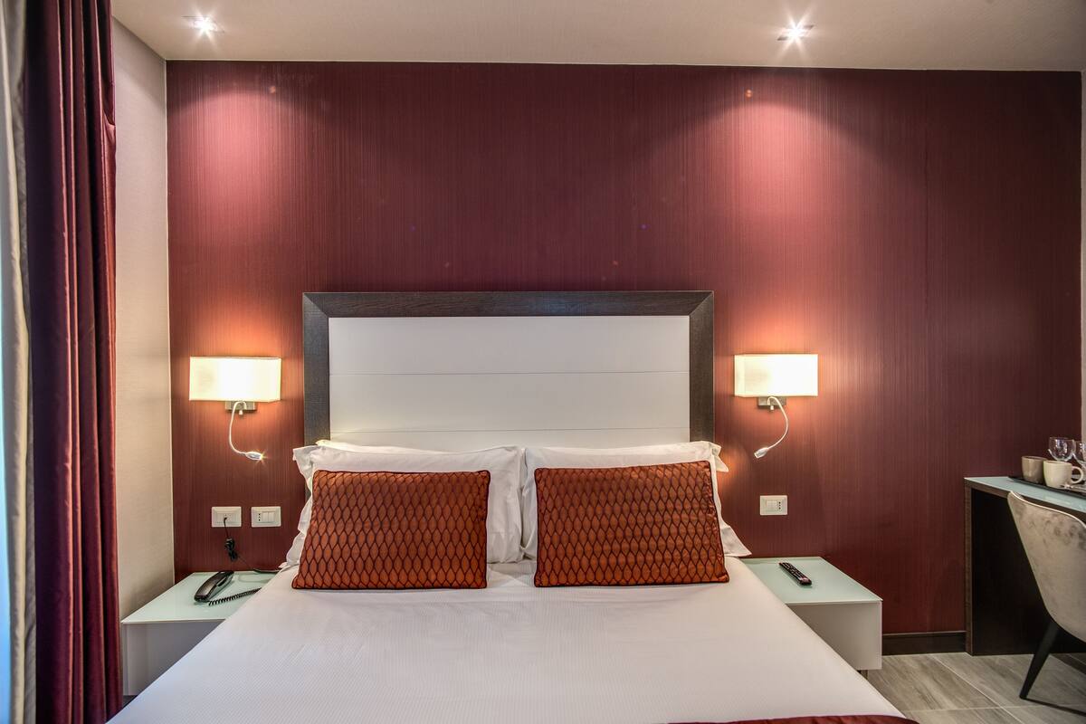 A hotel room with a large bed, two bedside tables, a desk, and a chair.
