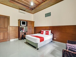 Una habitación de hotel con una cama grande, un armario de madera y un televisor en un estante.