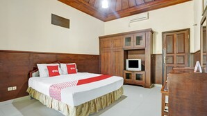 A hotel room with a wooden headboard, a bed with red and white bedding, a television on a wooden cabinet, and a wooden wardrobe. - OYO 3902 Pondok 828 Residence (Denpasar)